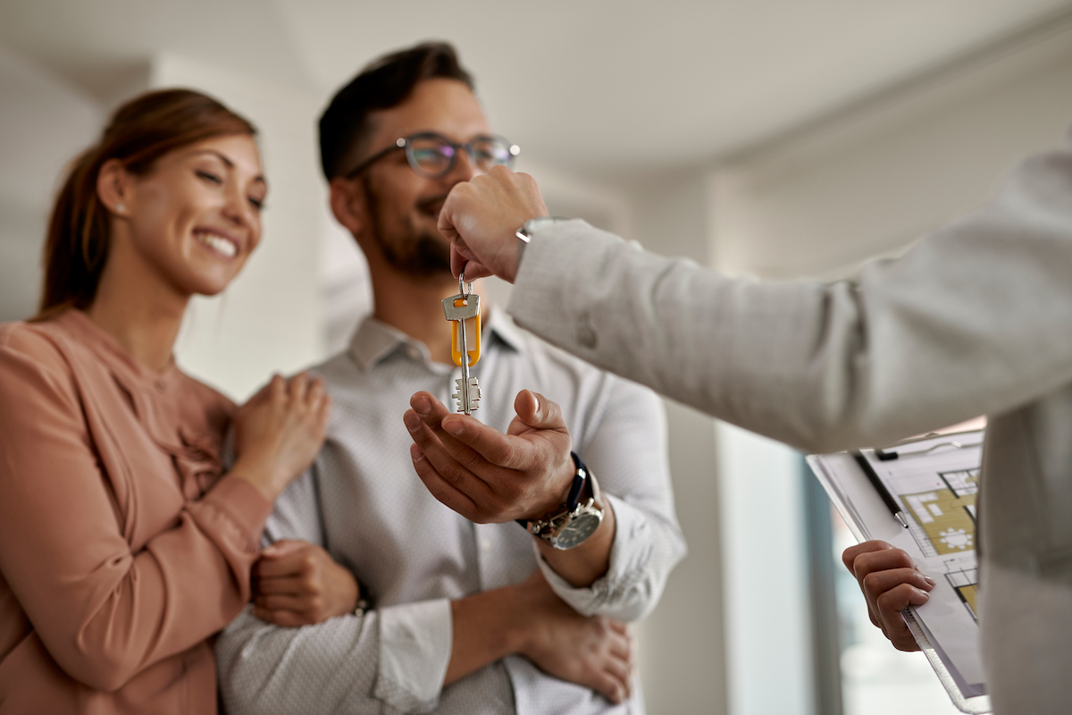 Close-up of real estate agent giving new house keys to a couple.