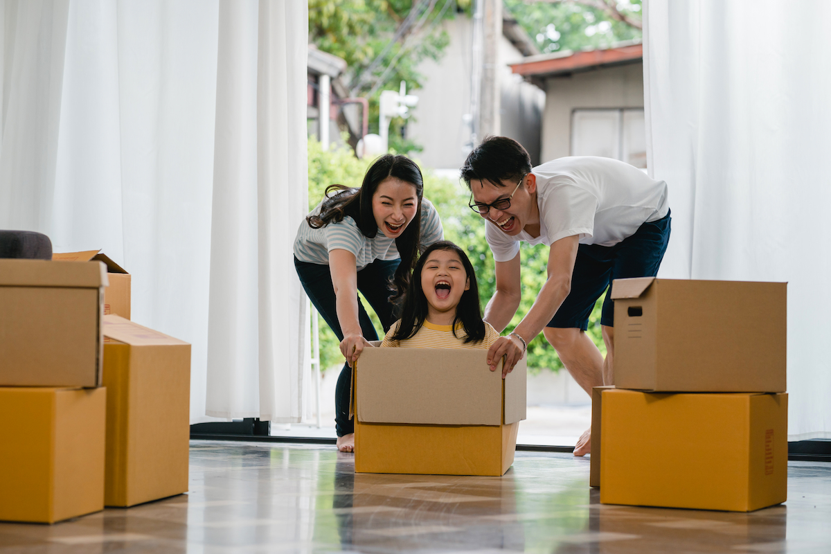 Happy Asian young family having fun laughing moving into new hom